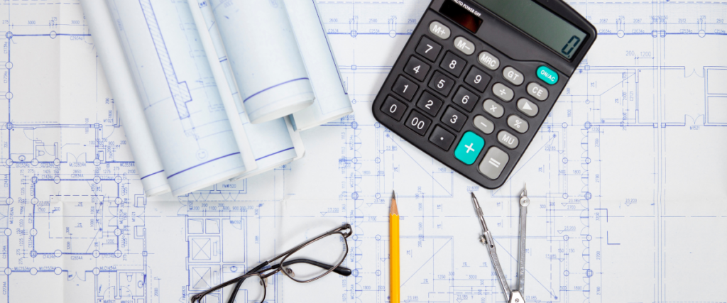 A blue print, calculator, and pencil on a desk to plan a commercial construction budget.